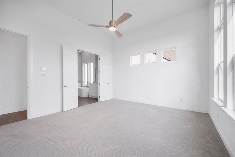 Primary bedroom with  carpet, ensuite bathroom, and ceiling fan