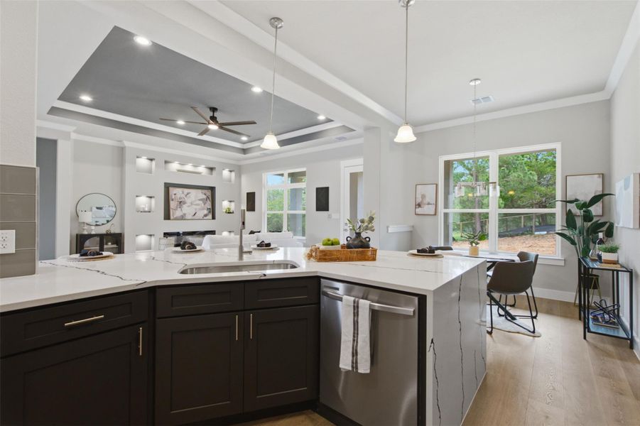 An open-concept kitchen with a breakfast bar, gleaming countertops, and hardwood flooring seamlessly transitions to a sun-filled living area. An open-concept kitchen with a breakfast bar, gleaming countertops, and hardwood flooring seamlessly transitions to a sun-filled living area.