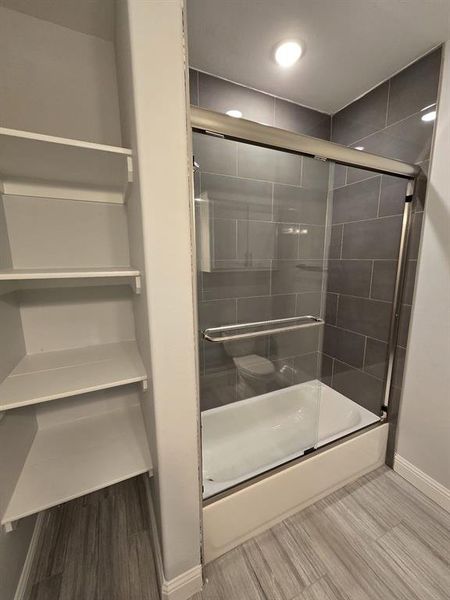 Bathroom with shower / bath combination with glass door and hardwood / wood-style floors