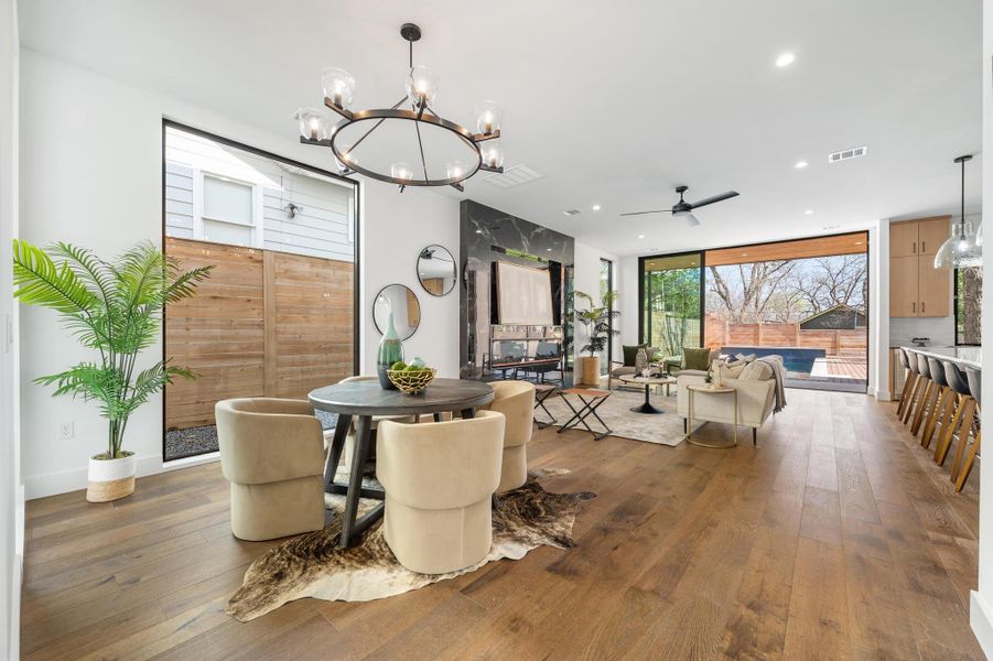 Dining space featuring hardwood / wood-style floors, floor to ceiling windows, ceiling fan with notable chandelier, and visible vents