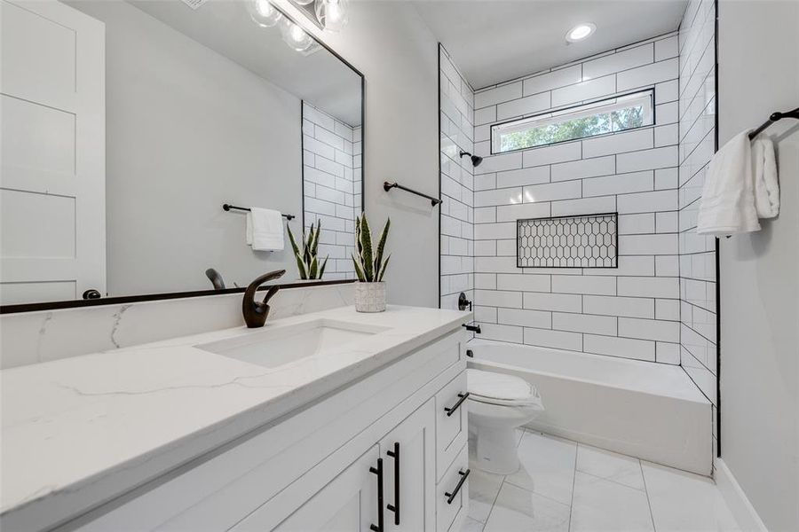 Full bathroom with vanity, tiled shower / bath combo, and toilet