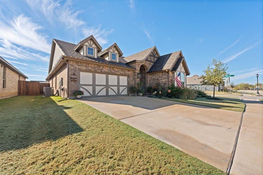 English style home with brick siding, concrete driveway, roof with shingles, and an attached garage