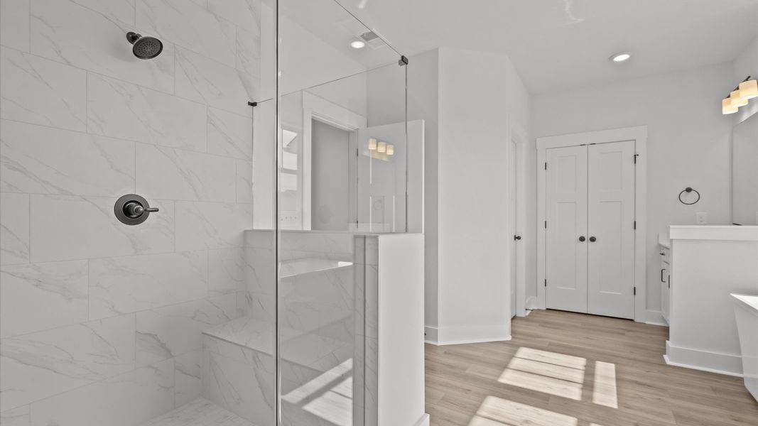 Elegant primary bathroom featuring a spacious tiled walk-in shower, soaking tub, and separate vanities
