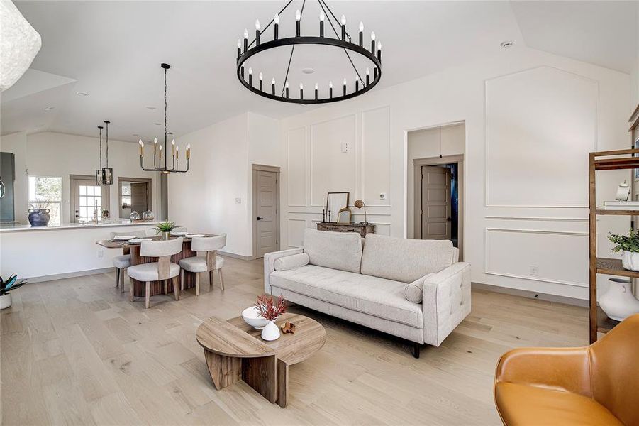 Living room featuring lofted ceiling, a chandelier, and light wood-style floors