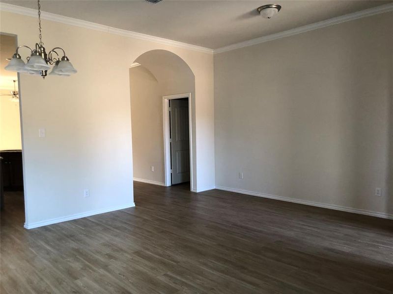 Spare room featuring dark hardwood / wood-style flooring, ornamental molding, and an inviting chandelier