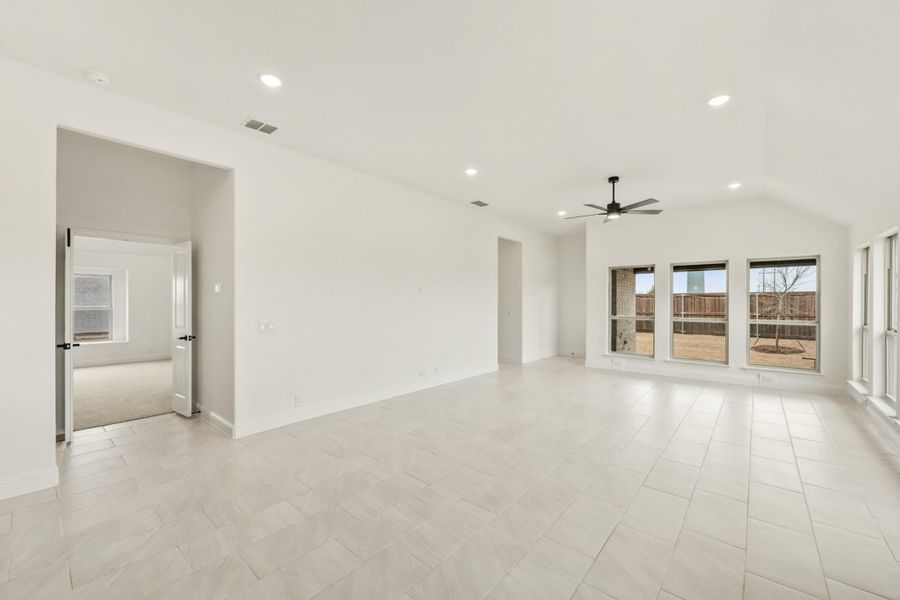 Open living room with tile floors, ceiling fan, recessed lighting, and large backyard-facing windows