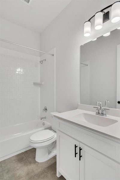 Full bathroom featuring tiled shower / bath combo, tile patterned floors, toilet, and vanity