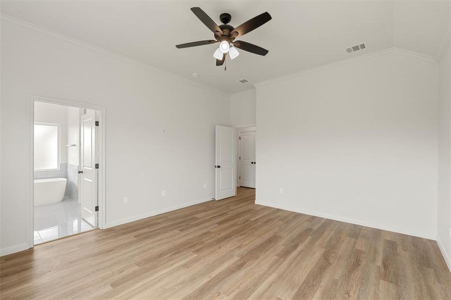 Unfurnished bedroom with ornamental molding, light wood finished floors, ceiling fan, ensuite bathroom, and lofted ceiling Unfurnished bedroom with ornamental molding, light wood finished floors, ceiling fan, ensuite bathroom, and lofted ceiling
