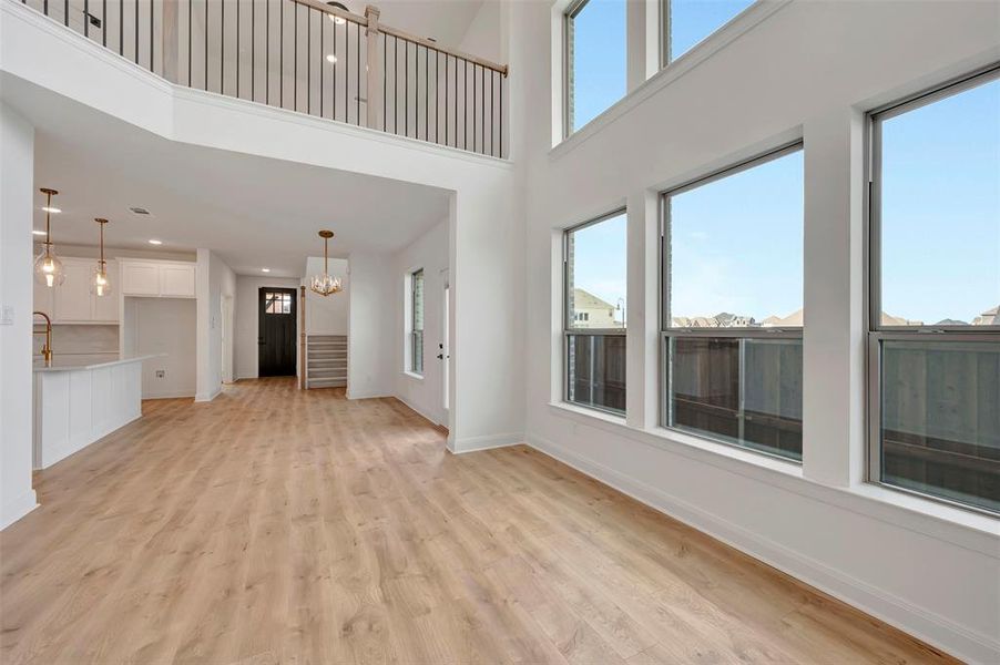 Unfurnished living room featuring light wood-style floors, a high ceiling, and a chandelier