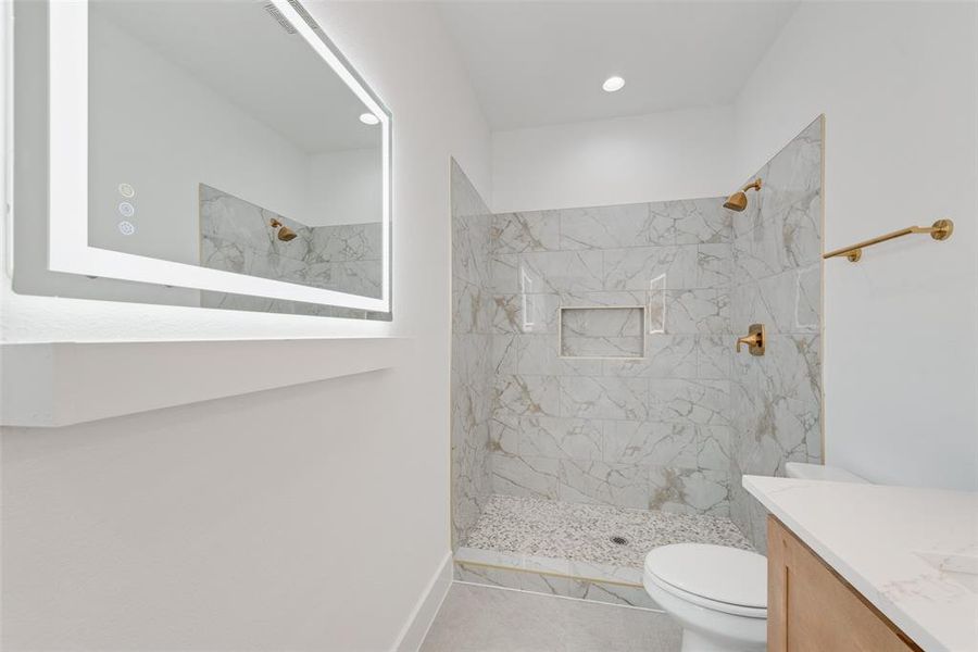 Bathroom with tile patterned flooring, toilet, a tile shower, and vanity