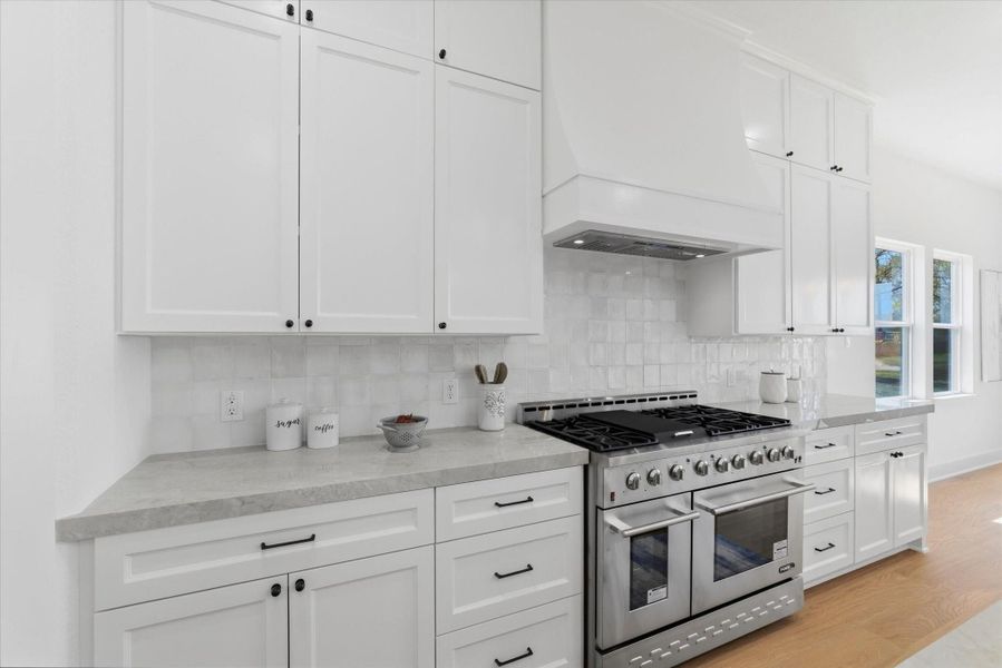 Kitchen featuring a 48-inch professional-style range, custom cabinetry extending to the ceiling, and elegant porcelain countertops.