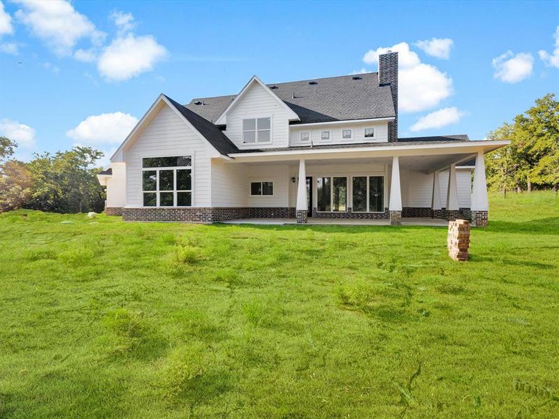 Rear view of property featuring a patio, a yard, a chimney, and a shingled roof Rear view of property featuring a patio, a yard, a chimney, and a shingled roof