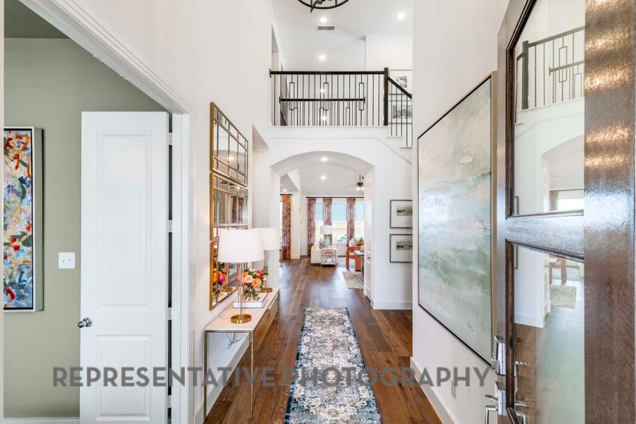 Hallway featuring recessed lighting, a towering ceiling, arched walkways, visible vents, and wood finished floors Hallway featuring recessed lighting, a towering ceiling, arched walkways, visible vents, and wood finished floors