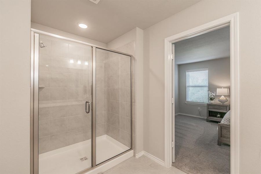 Ensuite bathroom with a shower stall and light tile patterned floors
