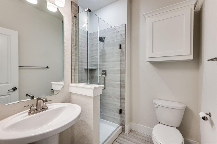 Bathroom with a sink, a stall shower, toilet, and baseboards Bathroom with a sink, a stall shower, toilet, and baseboards