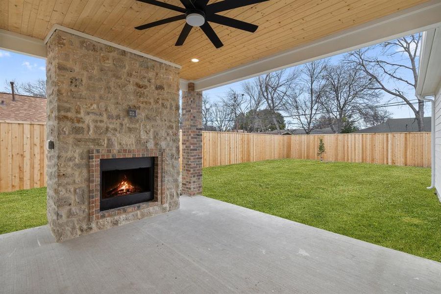 A covered patio complete with a cozy fireplace for outdoor gatherings.