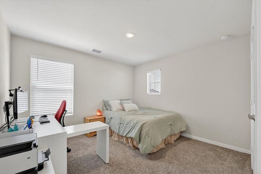Carpeted bedroom featuring a desk and baseboards