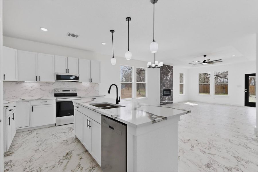 Kitchen featuring stainless steel appliances, suspended lighting, white cabinetry