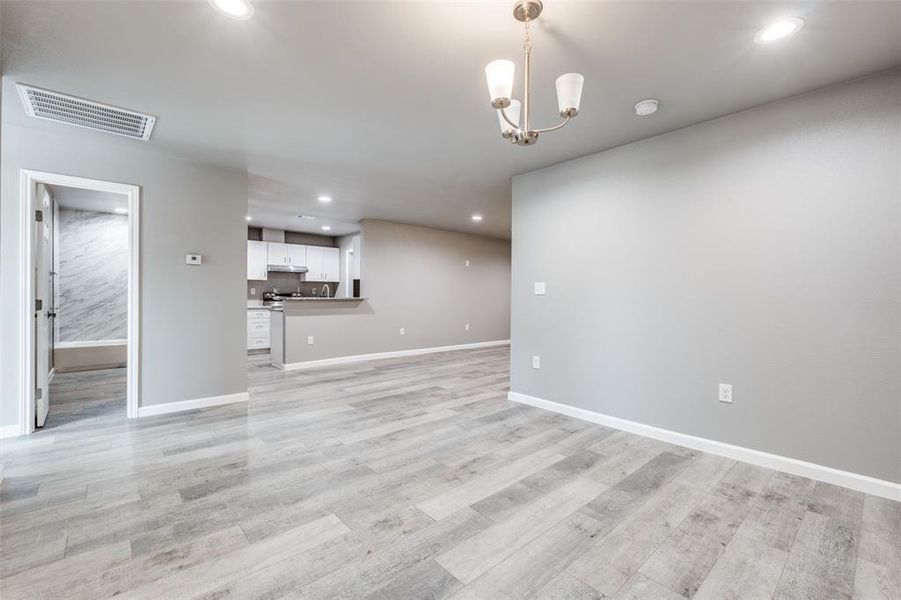 Unfurnished living room featuring a notable chandelier and light hardwood / wood-style flooring