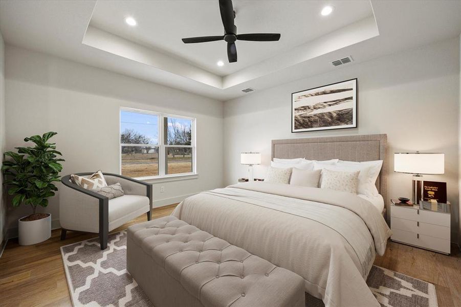 Bedroom featuring ceiling fan, a raised ceiling, and light wood-type flooring