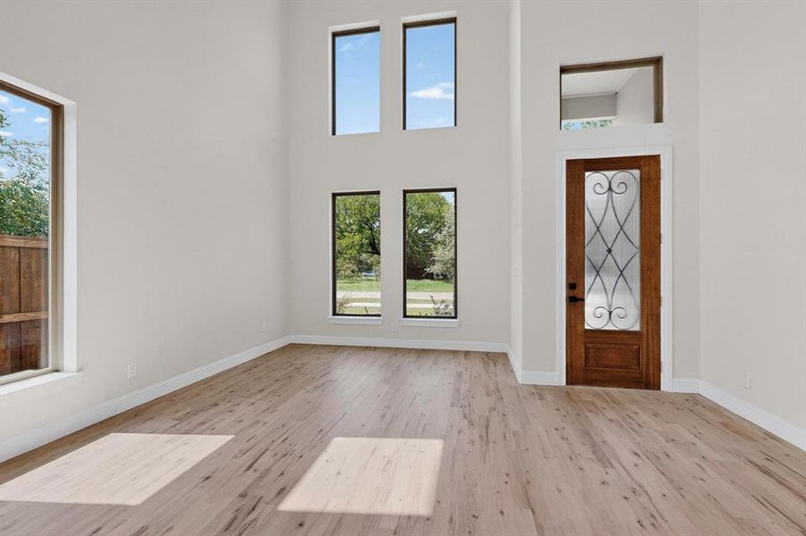 Foyer entrance featuring light wood-type flooring and a high ceiling Foyer entrance featuring light wood-type flooring and a high ceiling