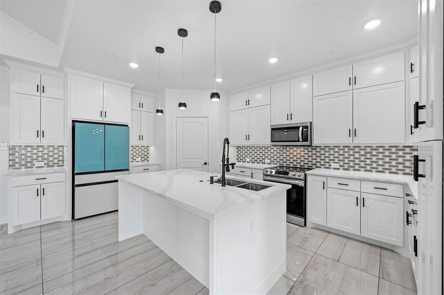 Kitchen featuring stainless steel appliances, a center island with sink, white cabinetry, and sink