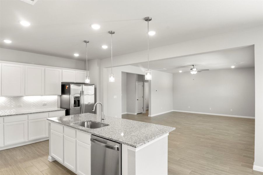 Kitchen featuring appliances with stainless steel finishes, a sink, a center island with sink, ceiling fan, and tasteful backsplash