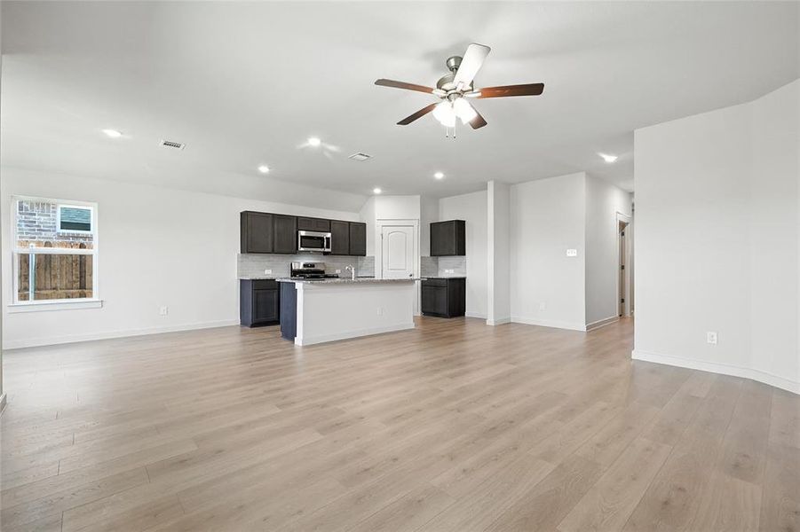 Unfurnished living room featuring a ceiling fan, light wood-style flooring, and recessed lighting