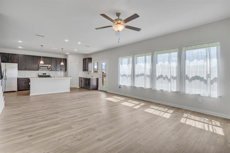 Unfurnished living room featuring light wood-type flooring and ceiling fan