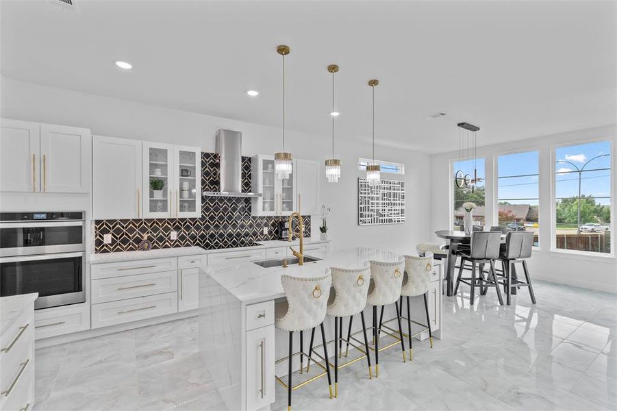 Modern kitchen featuring white cabinetry, a large center island with seating, a patterned backsplash, and stainless steel appliances