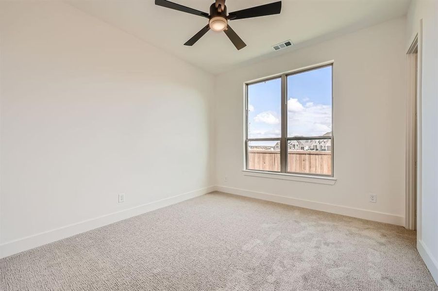 Carpeted empty room featuring ceiling fan