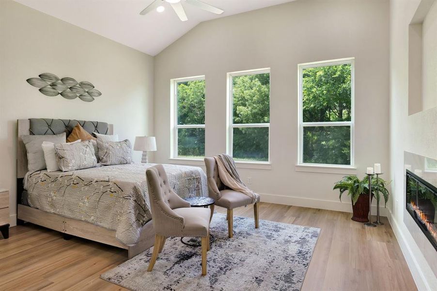 Vaulted ceilings with a ceiling fan, three large windows, wood-finish flooring, and a built-in linear fireplace Vaulted ceilings with a ceiling fan, three large windows, wood-finish flooring, and a built-in linear fireplace