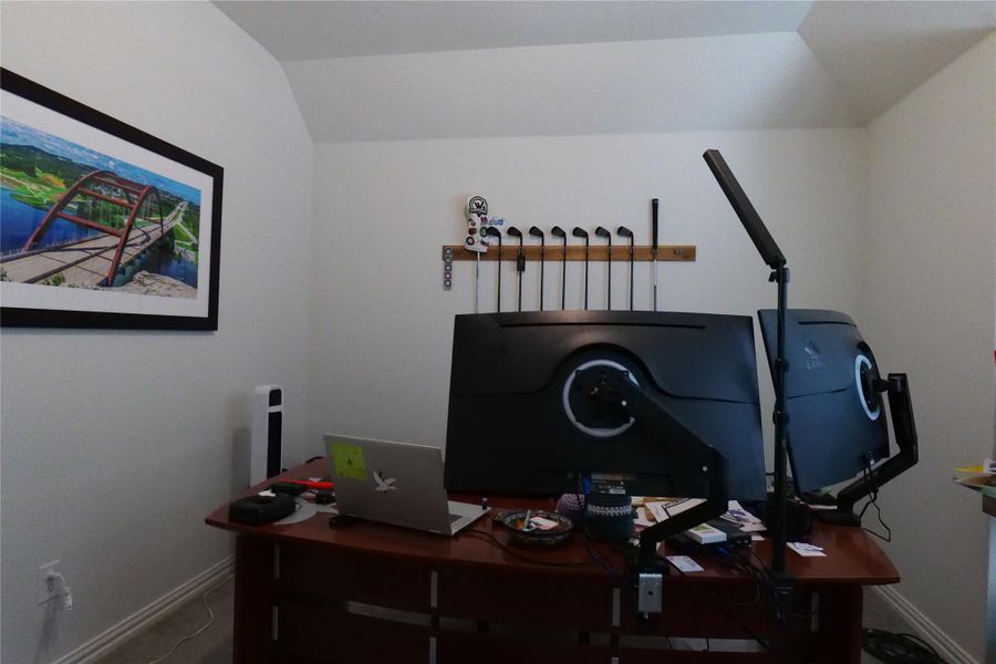 An inviting study features a dedicated workspace beneath high, angled ceilings.