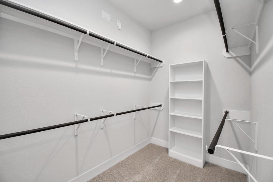 Walk-in closet that epitomizes luxury and practicality. This generously sized space features built-in shelving, offering abundant room for impeccable organization. High ceilings and recessed lighting create a bright and welcoming ambiance. Sample photo of completed home with similar floor plan. Actual colors and selections may vary.
