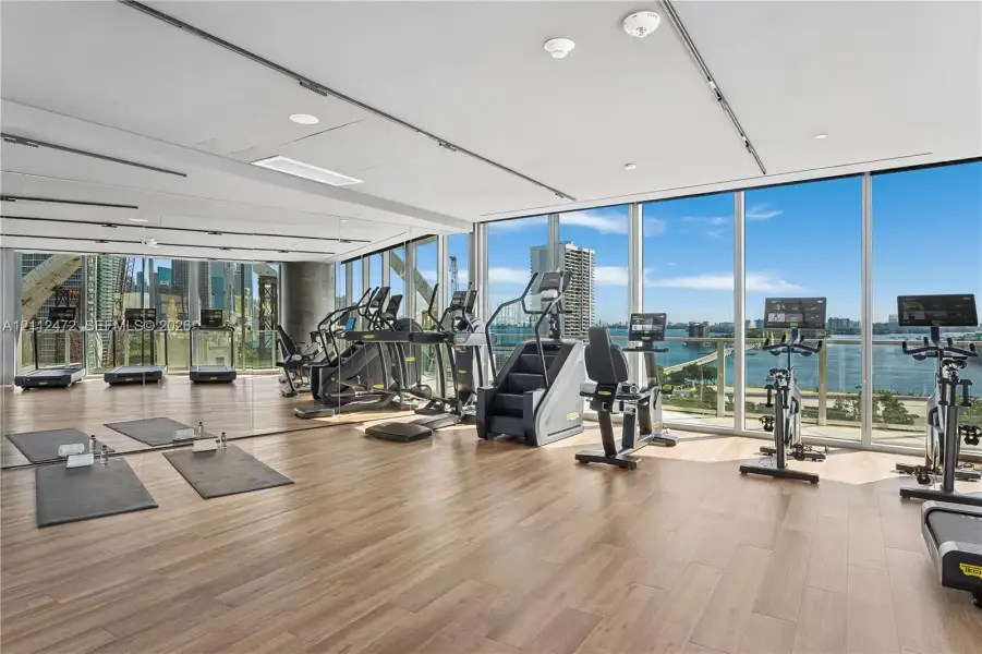 Fitness center featuring floor-to-ceiling windows, wood-finish flooring, recessed lighting, and mirrored walls