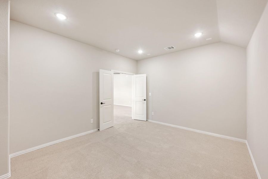 Empty bedroom with beige carpet, gray walls, recessed lighting, and open white double doors Empty bedroom with beige carpet, gray walls, recessed lighting, and open white double doors