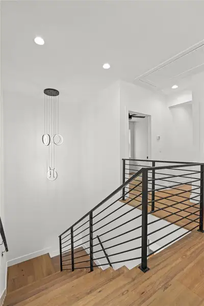 Modern wood flooring and sleek black railings frame this stylish interior staircase.
