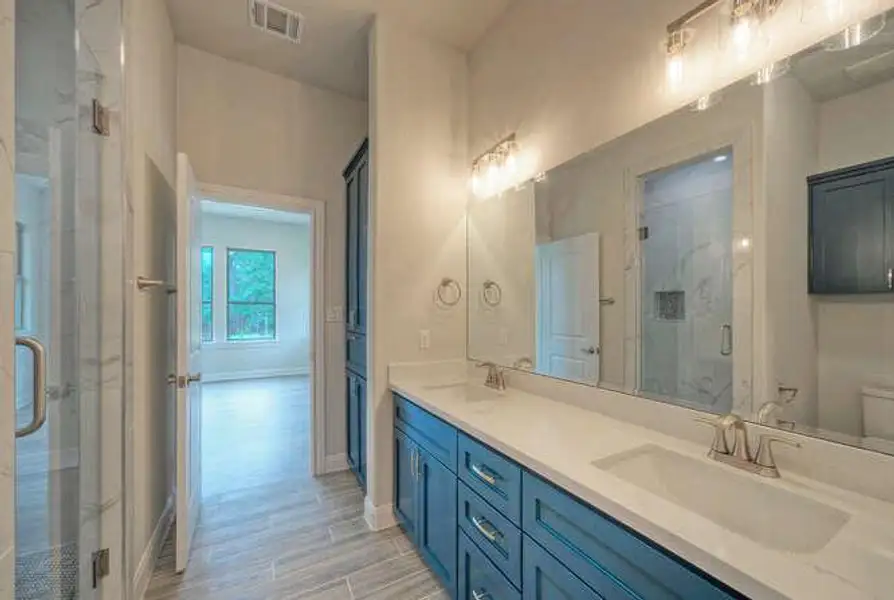 Full bathroom featuring double vanity, a shower stall, and wood finished floors