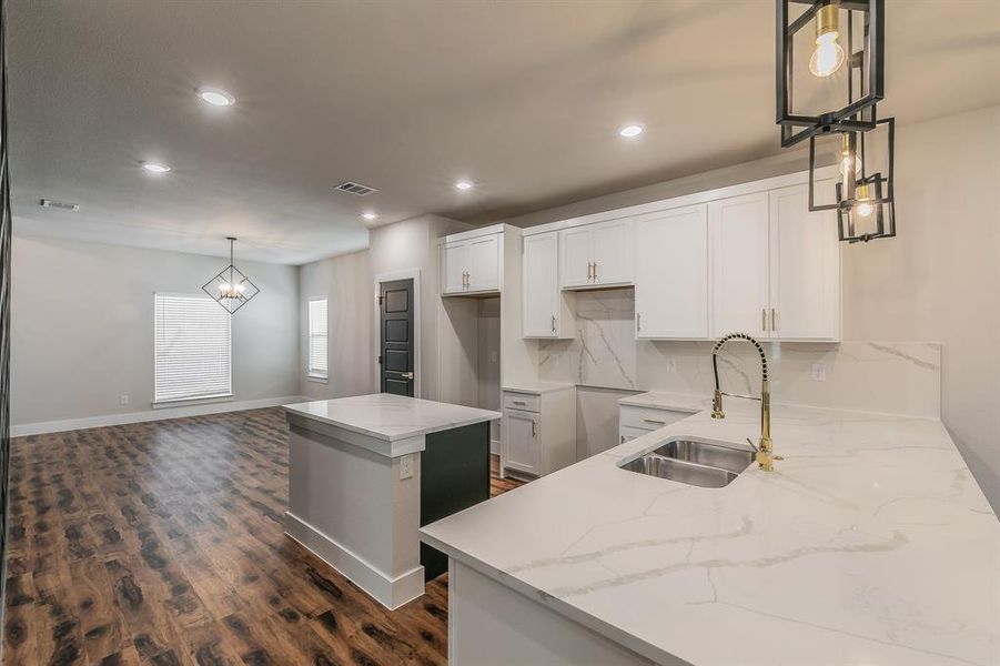 Kitchen featuring pendant lighting, dark wood-type flooring, white cabinets, sink, and a kitchen island