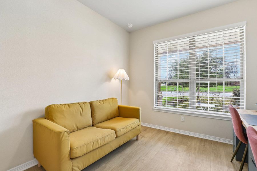 A well-lit sitting area with wide windows overlooking green streetscapes.