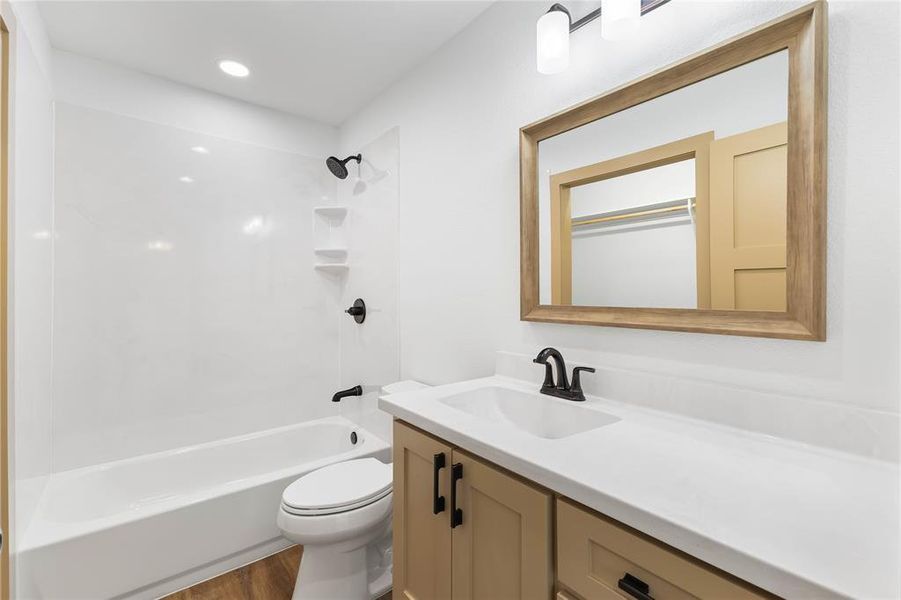 Bathroom featuring  shower combination, vanity, dark wood finished floors, and recessed lighting