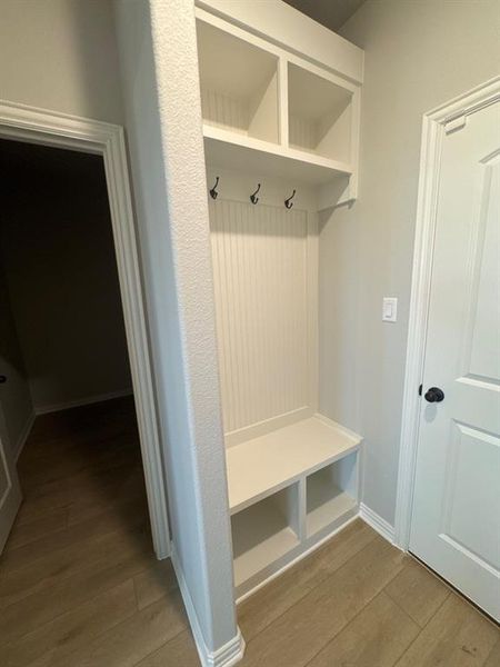 Built-in mudroom bench with cubby storage, beadboard backing, and overhead shelving featuring integrated coat hooks