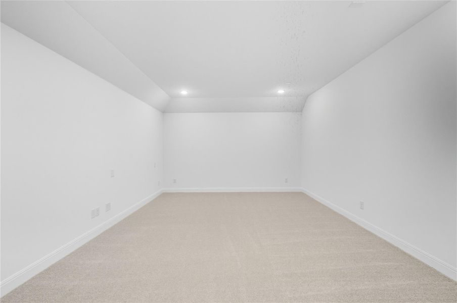Empty room with light colored carpet, vaulted ceiling, and recessed lighting
