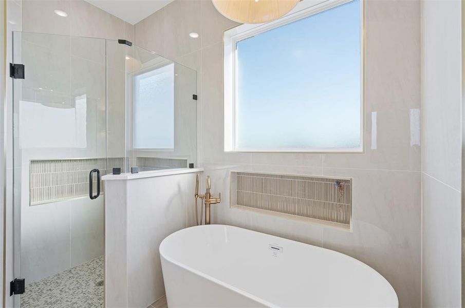 Bathroom featuring shower with separate bathtub and tile walls