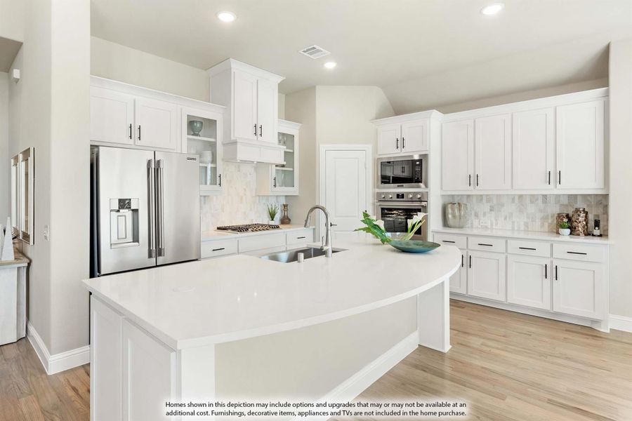 Kitchen with white cabinets, large curved island, stainless steel appliances, and light wood floors Kitchen with white cabinets, large curved island, stainless steel appliances, and light wood floors