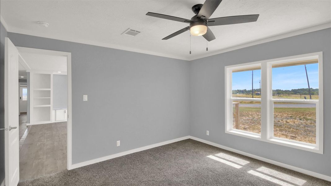 Plentiful natural light streams across the carpeted floor from large double windows.
