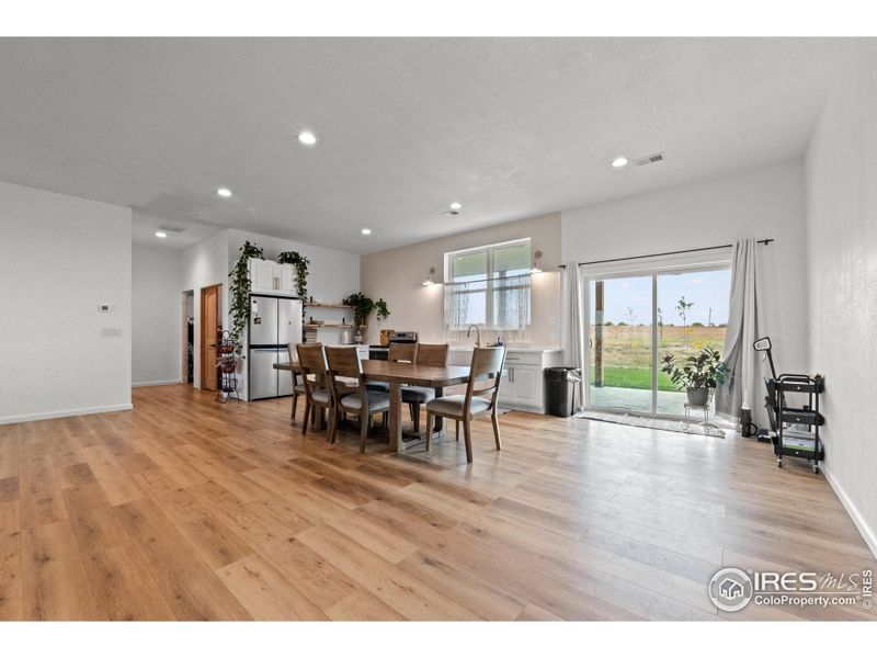 Expansive open-concept living and dining area with LVP flooring and recessed lighting, flowing naturally toward the private master suite for added comfort and convenience.