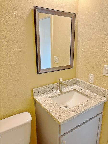 Half bath featuring a textured wall and vanity