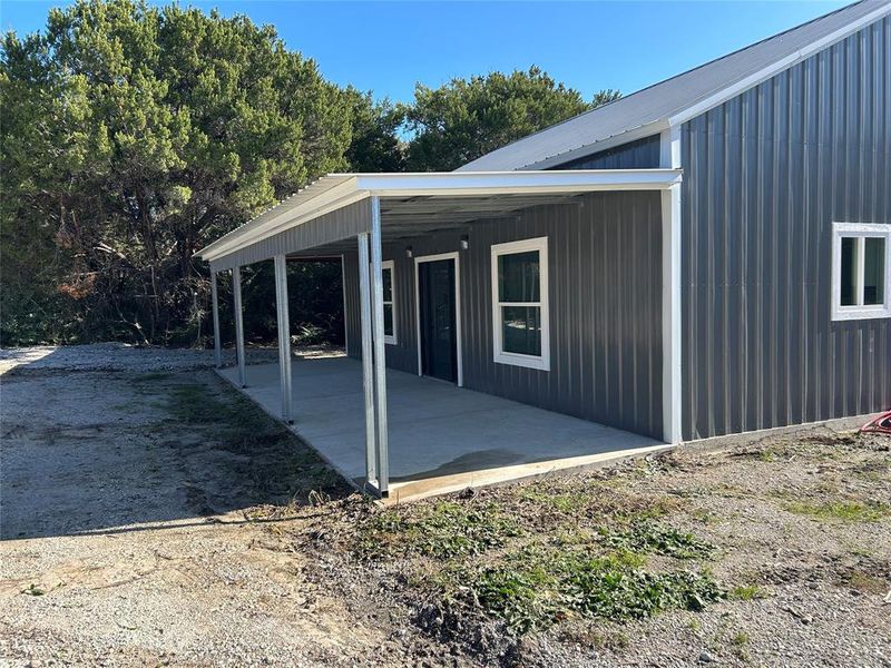View of property exterior featuring a metal roof and a patio area View of property exterior featuring a metal roof and a patio area