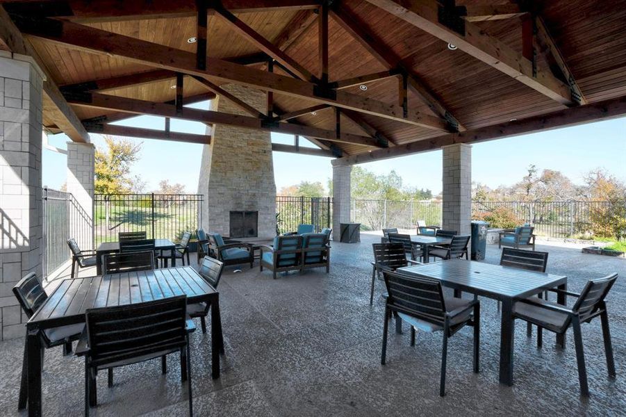 Exposed wood trusses anchor this sheltered concrete terrace alongside a monumental stone fireplace.